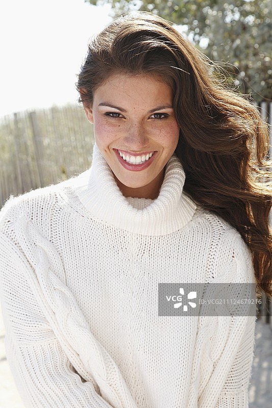 在户外身穿白色针织高领套头衫的年轻女子图片素材
