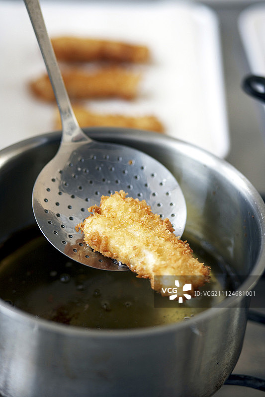 从食用油中捞出的炸鱼条图片素材