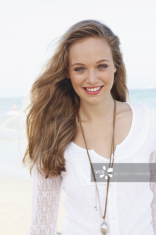 一位身穿白色蕾丝开衫和白色T恤的年轻女人图片素材