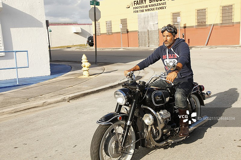 身穿连帽衫的男子坐在摩托车上图片素材