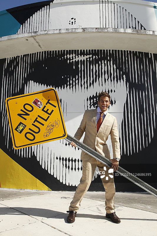 一位拿着“禁止通行”路牌的年轻男人图片素材