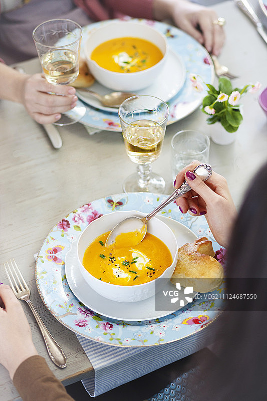 两个女人喝胡萝卜奶油汤，配以披萨面团制作的兔子图片素材