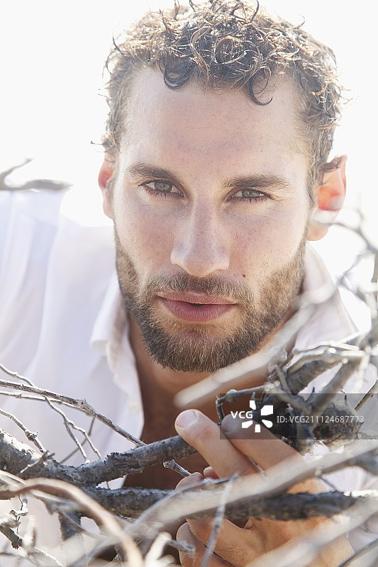 一个穿着白衬衫的年轻人拿着脆弱的树枝图片素材