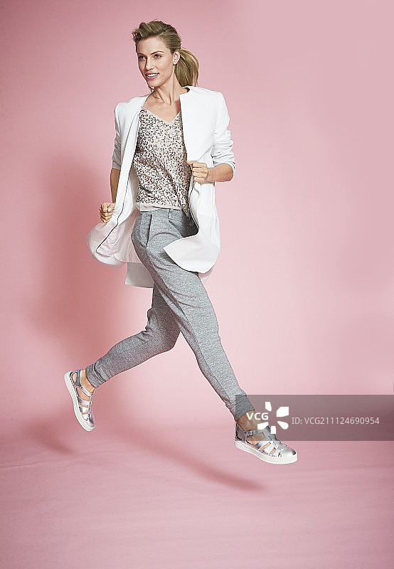 年轻女子身穿亮片上衣、运动裤和短外套图片素材