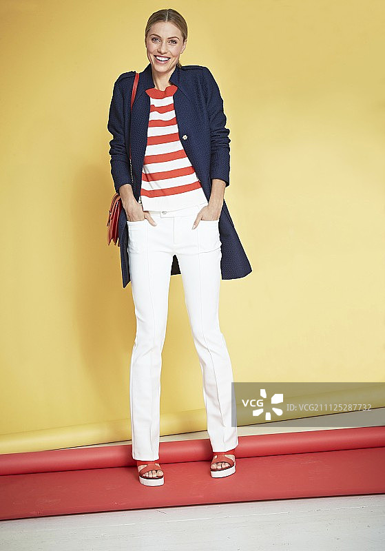 身穿条纹套头衫、白色长裤和蓝色短外套的女人图片素材