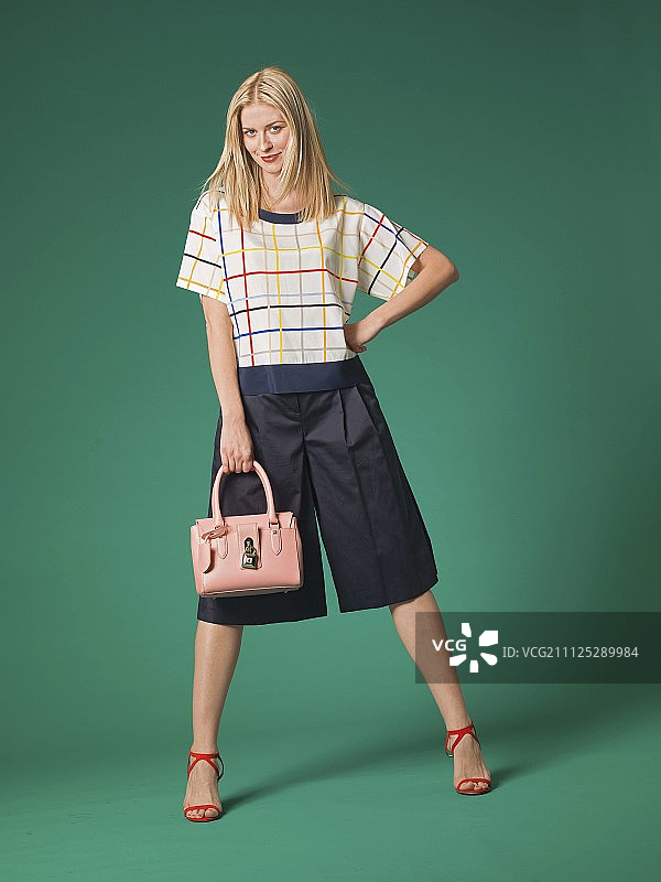 一位身穿宽松上衣、阔腿裤和凉鞋的金发女人图片素材