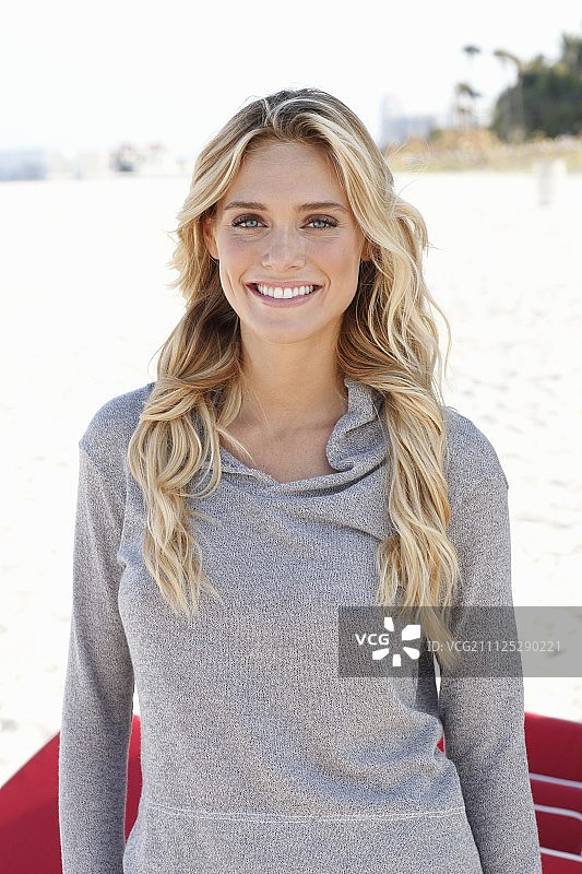 一位身穿灰色长袖帽衫的年轻金发女子图片素材