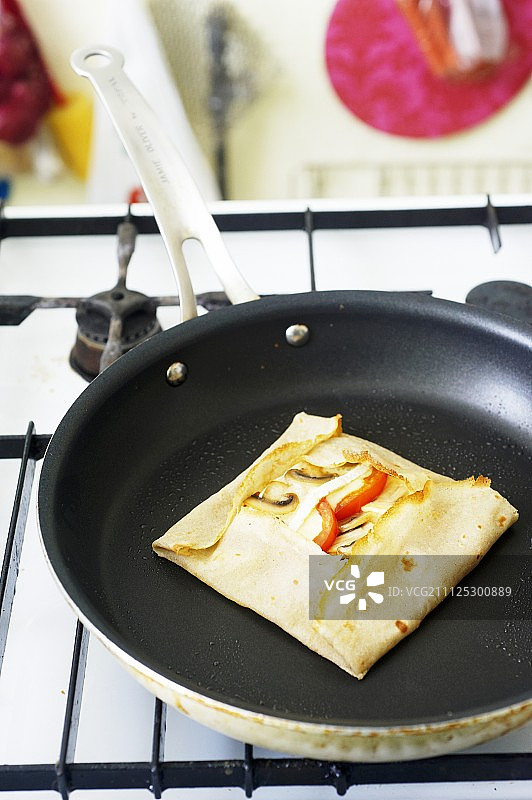 为学生烹饪：平底锅里的奶酪蔬菜馅饼图片素材
