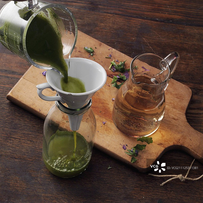 以希尔德加德·冯·宾根方式酿造的耧斗菜酒：将耧斗菜汁倒入瓶中图片素材