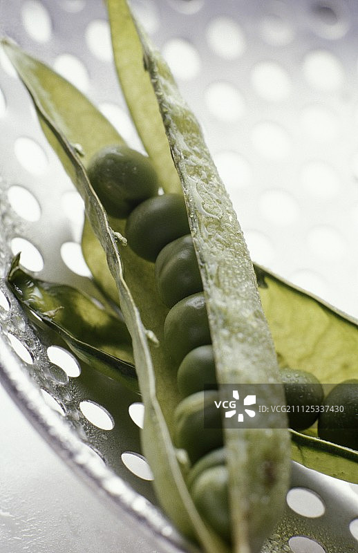 漏勺上的带荚豌豆图片素材