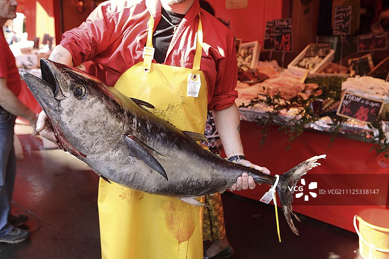 鱼贩在他市场摊位前拿着一条大鱼图片素材