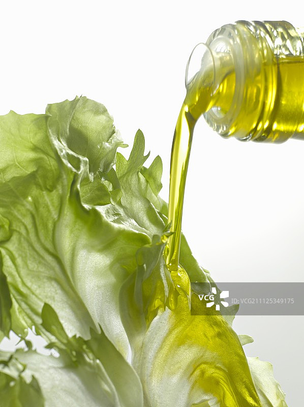 将橄榄油倒在生菜叶上图片素材