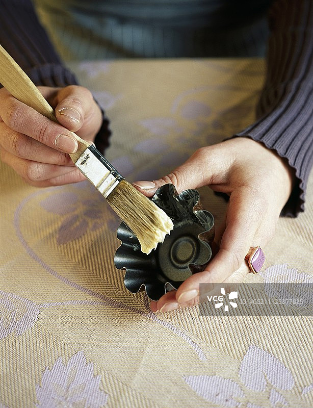 用刷子在模具上涂黄油图片素材