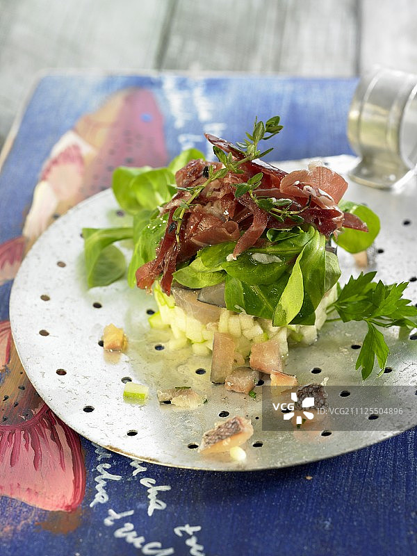 鳟鱼和苹果鞑靼配生菜沙拉和西班牙生火腿图片素材