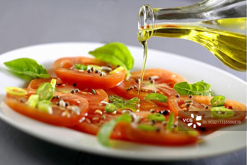 将橄榄油倒在番茄罗勒沙拉上图片素材