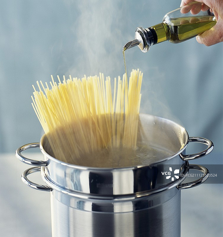 在烹饪的意大利面中加入一滴橄榄油图片素材