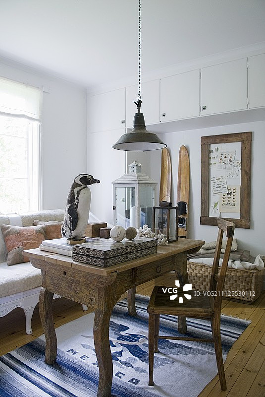 乡村风格室内：蓝白色地毯上的实木桌椅、复古吊灯和企鹅玩偶图片素材