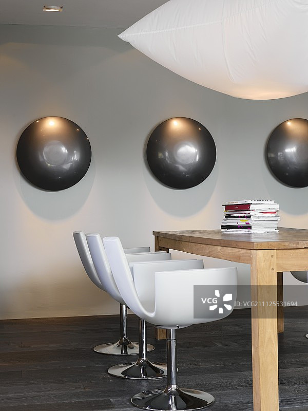 白色设计师椅，位于深色镶木地板上的大型木桌旁图片素材