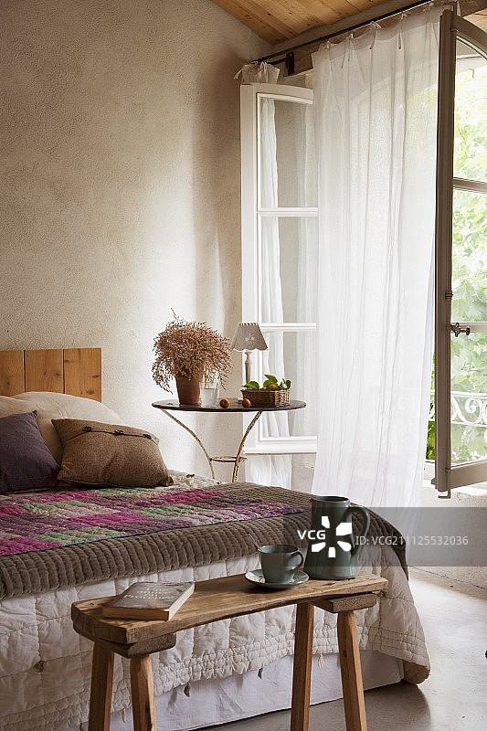 床尾的木制长椅和床罩，一侧是通风的窗帘图片素材