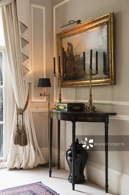 18世纪控制台桌上的青铜烛台和石灰墙上的古董画图片素材