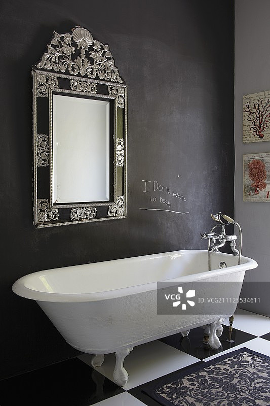 复古风格，带爪足的浴缸，位于格子地板上，背景是带框镜子的深色墙壁图片素材