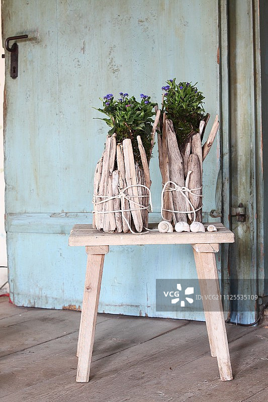 木制凳子上用漂木捆绑而成的创意花盆图片素材