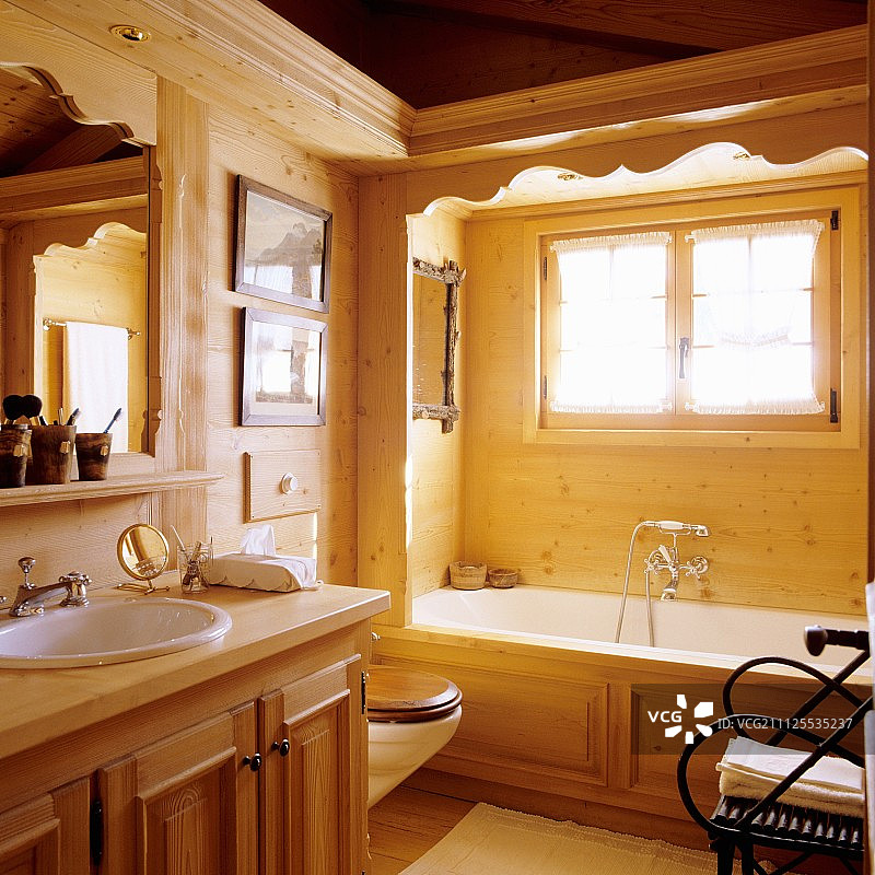 木屋浴室里，浴缸旁窗户下的实木底座洗手台图片素材