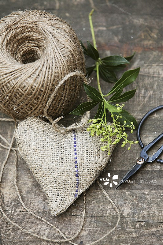 手缝心形粗麻布香袋、线轴和复古剪刀木质台面静物图片素材