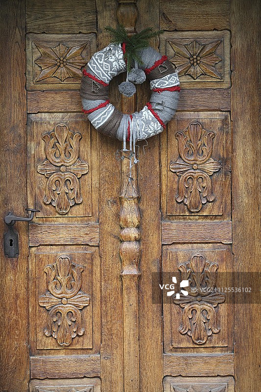 手工制作的节日花环在雕刻的木门上图片素材