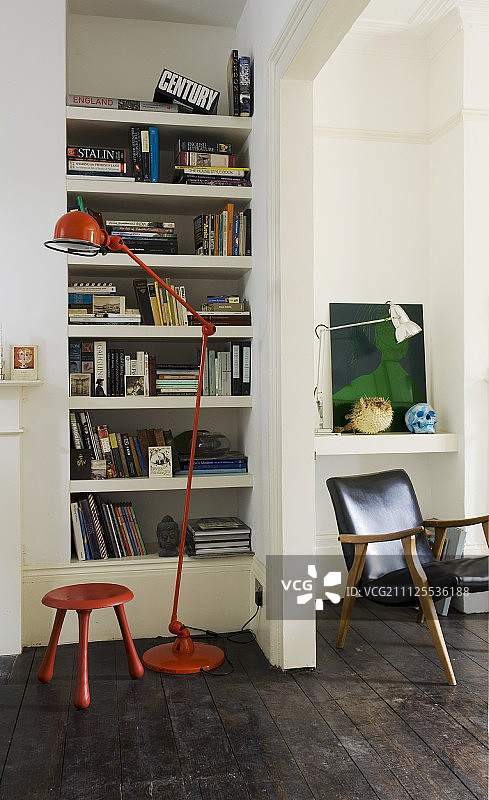 红色金属落地灯和红色凳子，前面是固定的书架，旁边是敞开的门口和复古扶手椅的景色图片素材