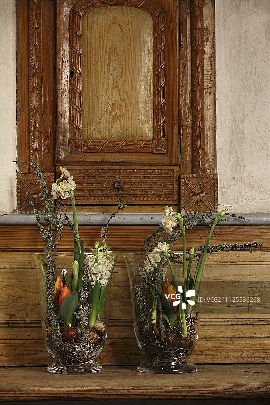 木凳上摆放着插有春花的两个大型玻璃花瓶图片素材
