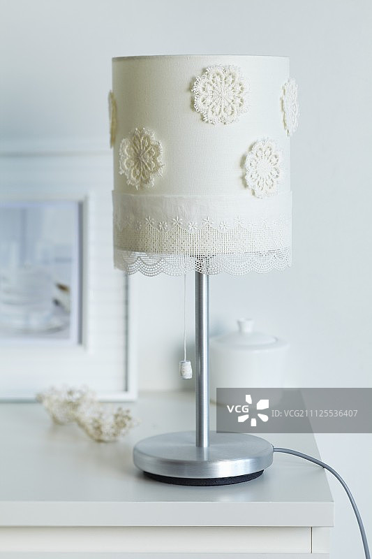用钩针编织的垫子和薄纱花边装饰的台灯灯罩图片素材
