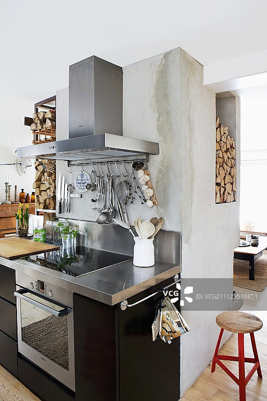 厨房中的炊具区域，配有不锈钢台面和混凝土烟囱背面的黑色正面，壁龛用于放置木柴图片素材