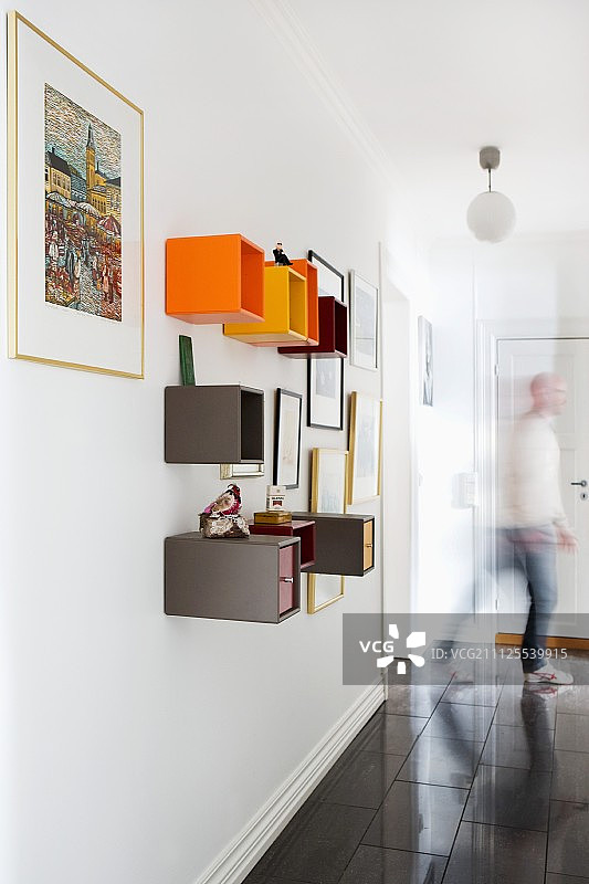 走廊墙壁上彩色立方体搁架单元；背景中的男人图片素材