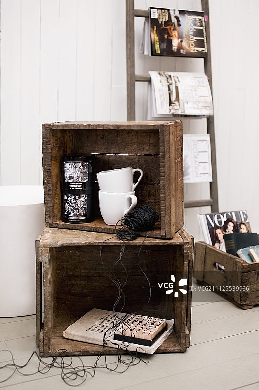 白色木墙前旧木箱中的复古装饰与梯子上的时尚杂志图片素材