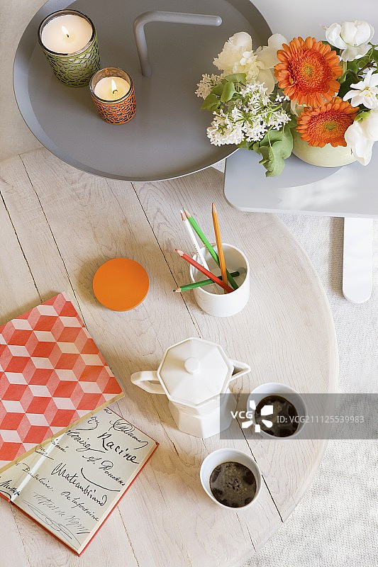 带有鲜花摆设、绿色和橙色蜡烛灯笼的白色咖啡桌和金属边桌图片素材