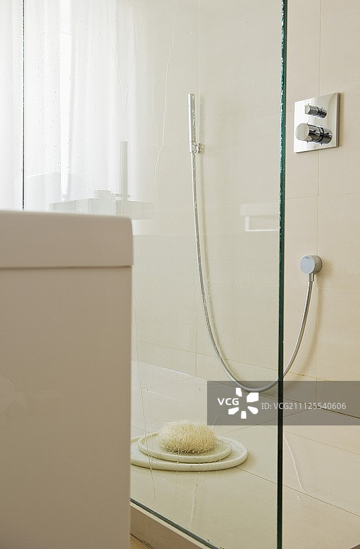 淋浴区玻璃隔断和设计师壁挂式水龙头配件特写图片素材