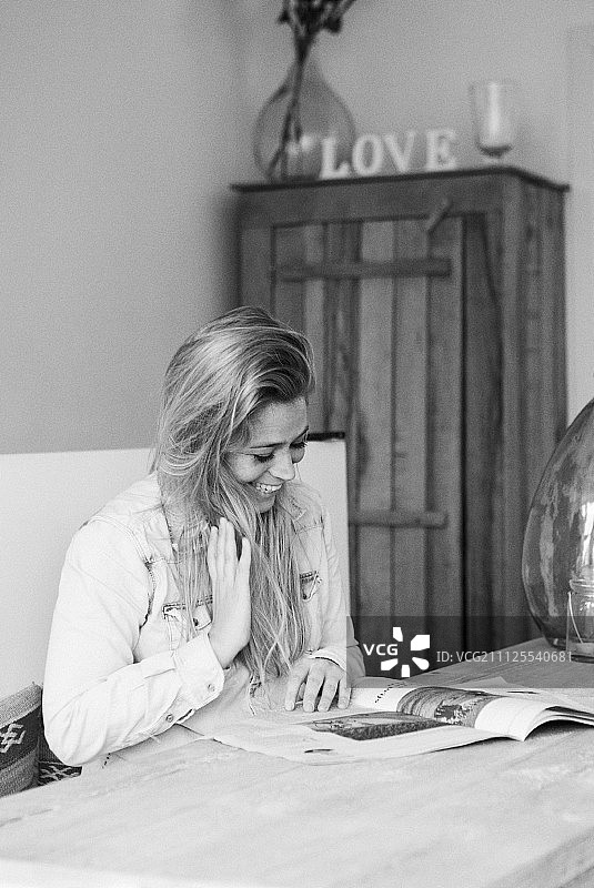 在桌旁阅读杂志的年轻女人（黑白照片）图片素材