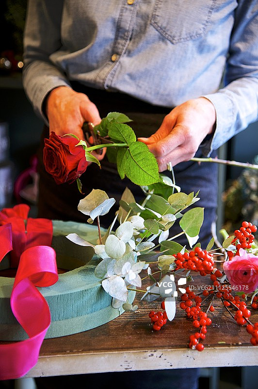 女子用花艺泡沫底座制作玫瑰花环图片素材