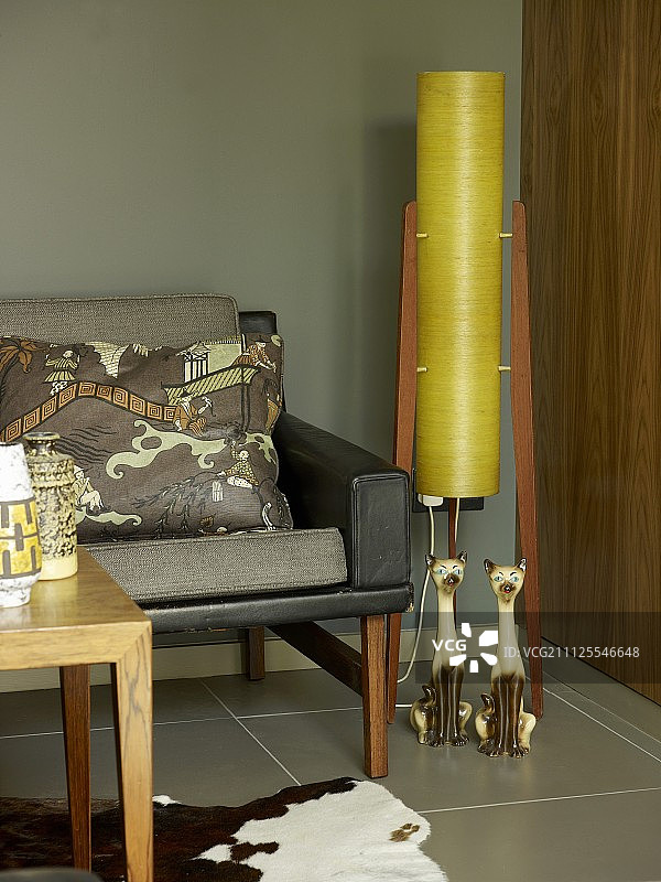 灰色沙发和靠垫一角，旁边有猫摆件和复古落地灯图片素材