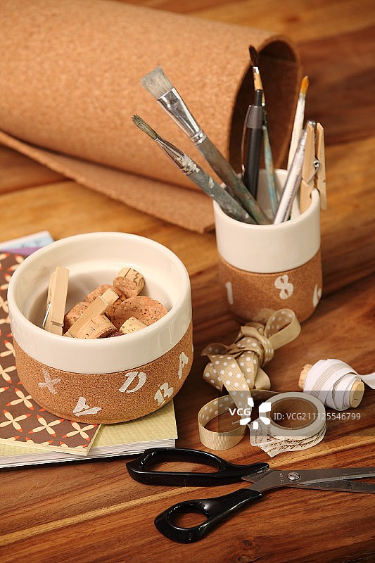 木桌上软木塞和画笔容器旁的工艺品用具图片素材