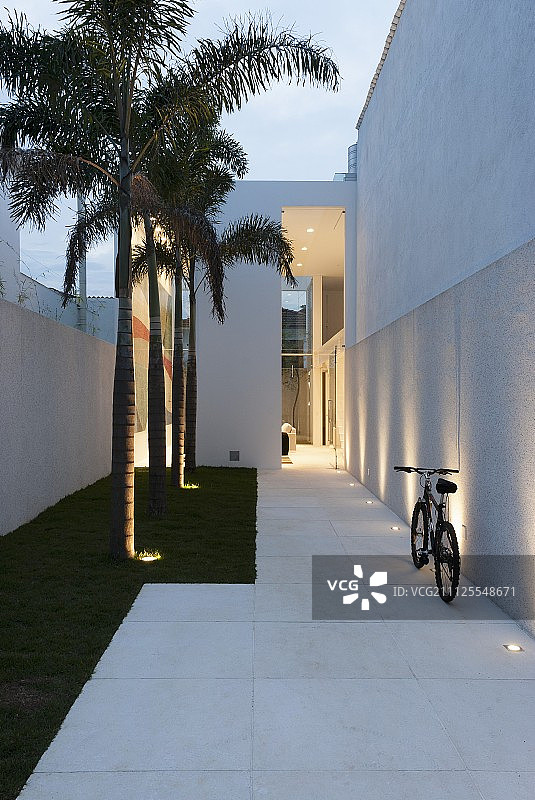 高耸白墙间的小路，带有嵌入式灯具和小型草坪图片素材