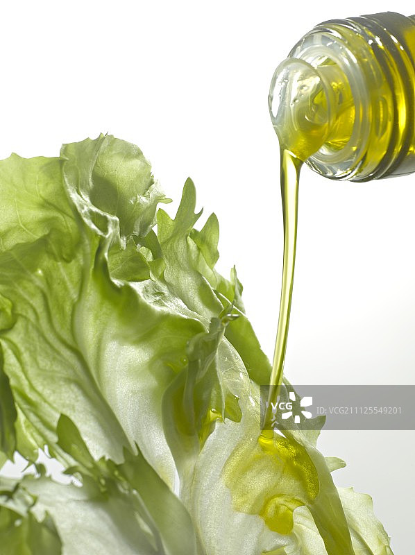 将橄榄油倒在生菜叶上图片素材