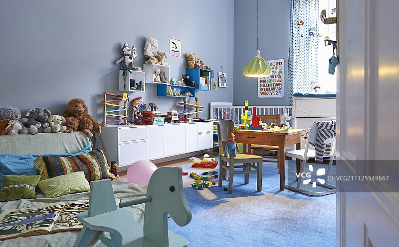粉蓝色宽敞的儿童卧室，配有色彩鲜艳的木制玩具和软玩具图片素材