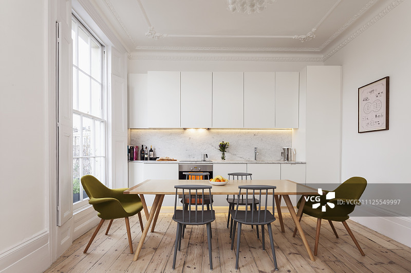 简约的白色厨房，位于带格子窗户的翻新公寓内，配有木地板和复古风格的用餐区图片素材