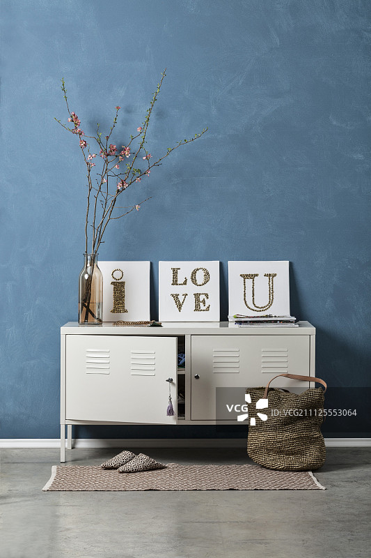 白色储物柜、蓝灰色墙壁与DIY装饰画的复古摆设图片素材