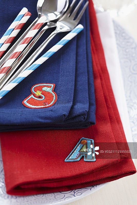 带有烫印首字母的彩色亚麻餐巾、餐具和吸管图片素材