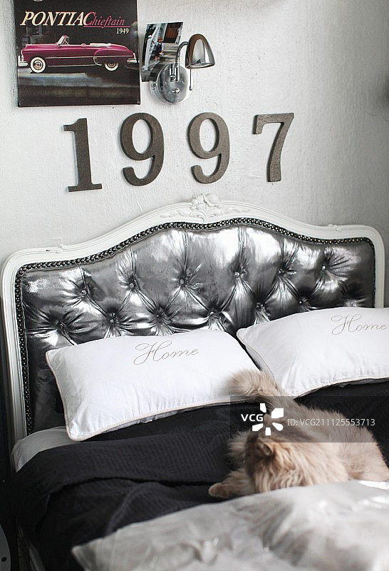 双人床采用银色软包弧形床头板；墙上装饰数字和复古灯具图片素材