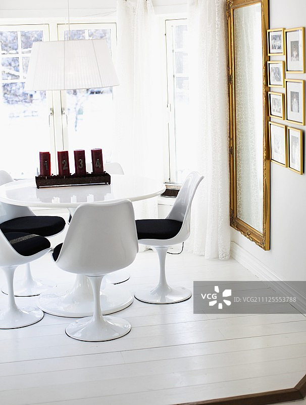 圆桌上的郁金香椅和圣诞蜡烛，墙上是镀金镜框图片素材