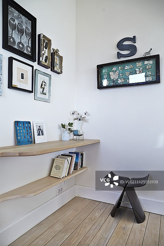 柳宗理设计的深色木蝴蝶凳，角落里书架上的书籍和装饰品图片素材